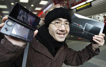 Тойохиса Ишихара (Toyohisa Ishihara), первый покупатель Nintendo 3DS, позирует корреспондентам в магазине электроники в Токио
